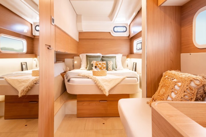 Cozy yacht cabin with a bed, throw pillows, and wood paneling.
