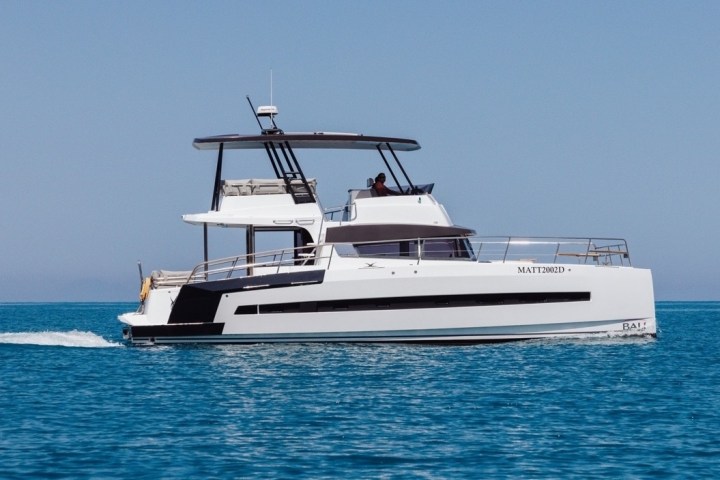 White catamaran motor yacht sailing on a calm, blue sea.